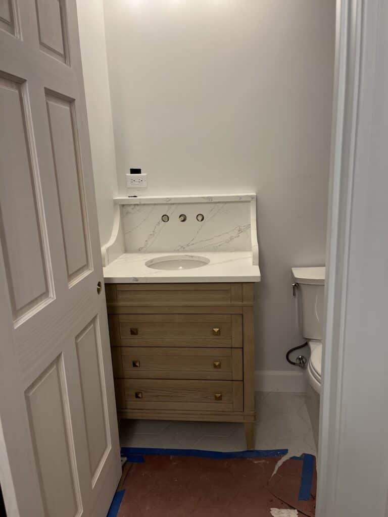 Modern bathroom featuring a wooden vanity and white countertop.