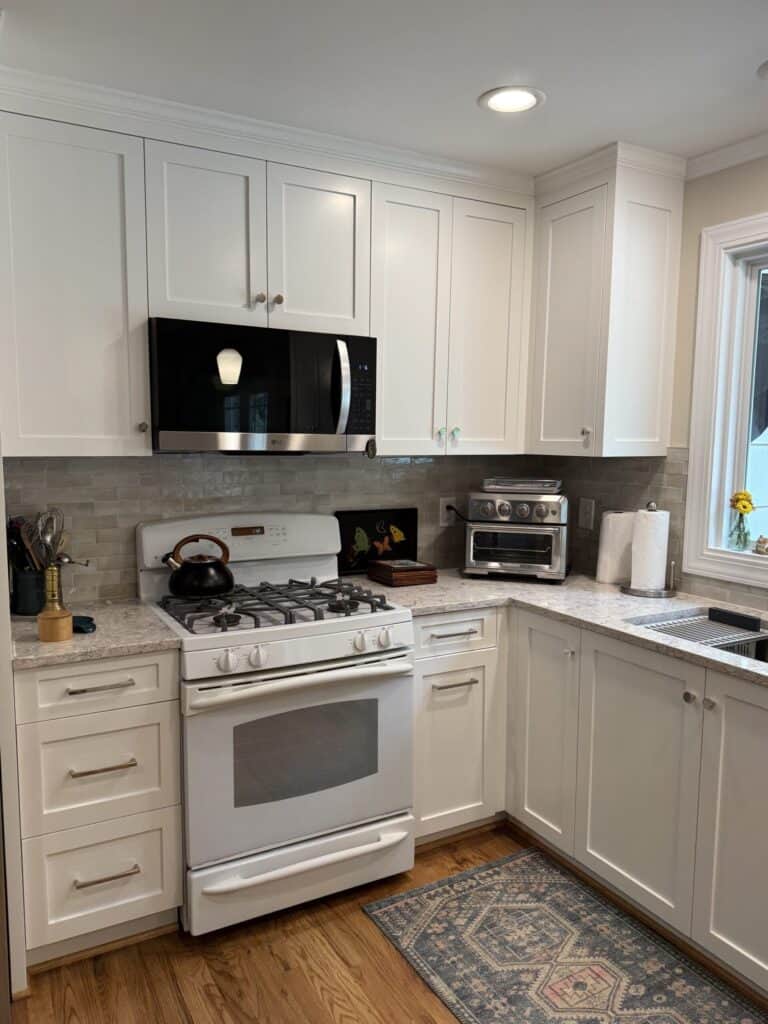 Modern kitchen with white cabinets and stainless steel appliances.