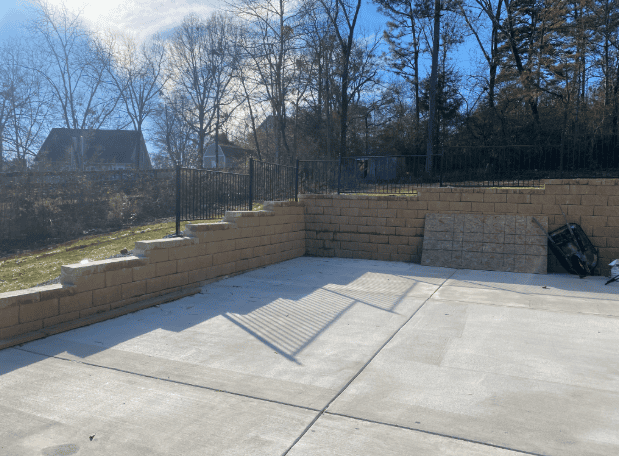 Spacious backyard patio with retaining wall and wooden fence