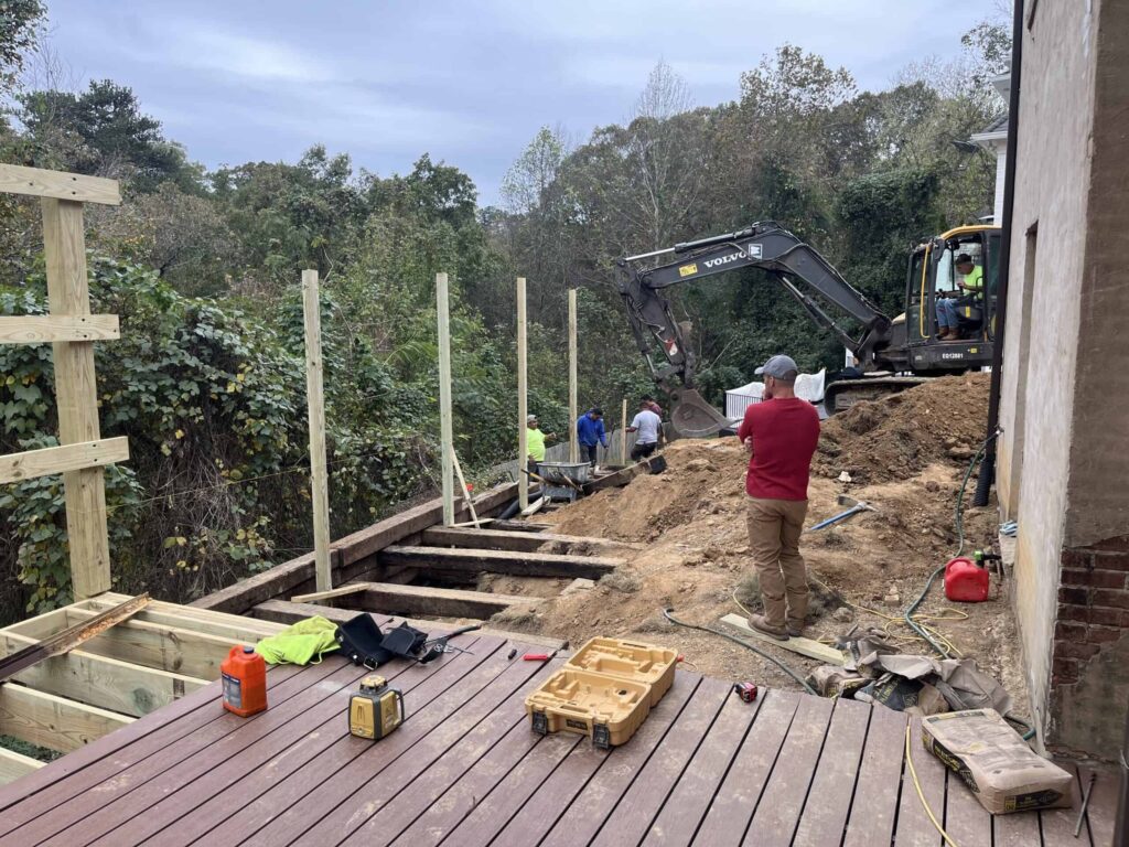 Construction workers building a deck with heavy machinery nearby.