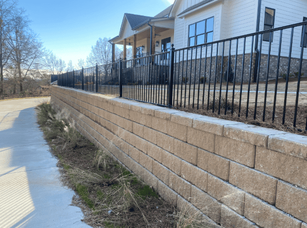 Modern house with a retaining wall and black fence.