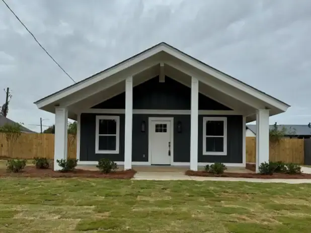 Stylish grey house with a front porch and landscaped yard.