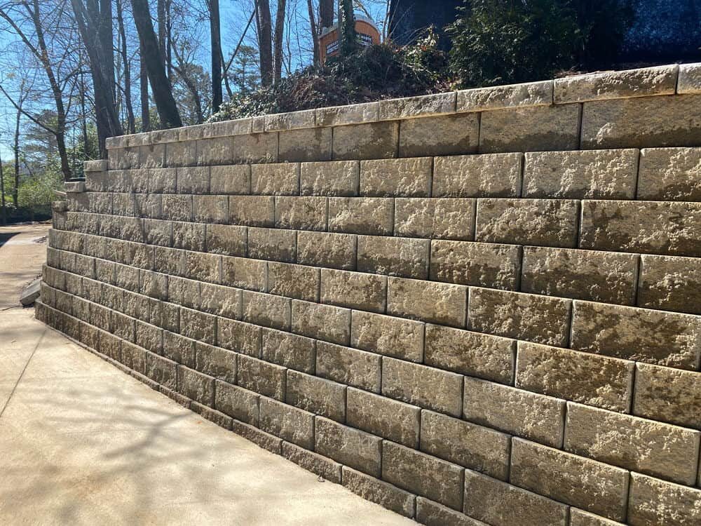 Textured stone wall with trees in background on a sunny day.