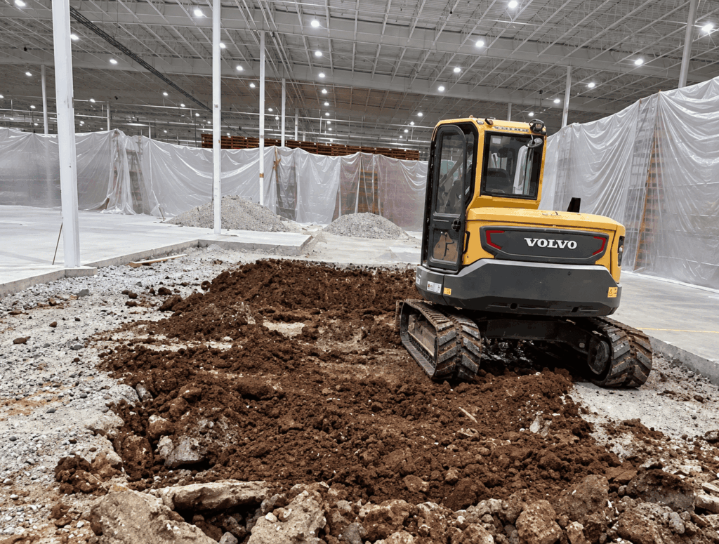 Excavator working on construction site with freshly dug soil.